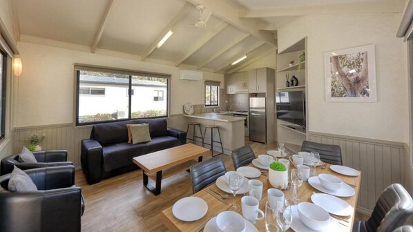 A modern living room with a sofa, coffee table, and dining area set for six.