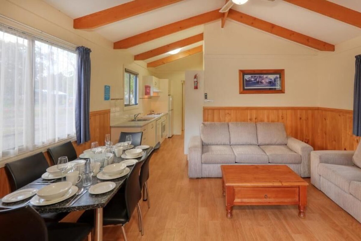 Ein gemütliches Wohnzimmer mit einer Couch, einem Holztisch und einem Esstisch, der für eine Mahlzeit gedeckt ist.