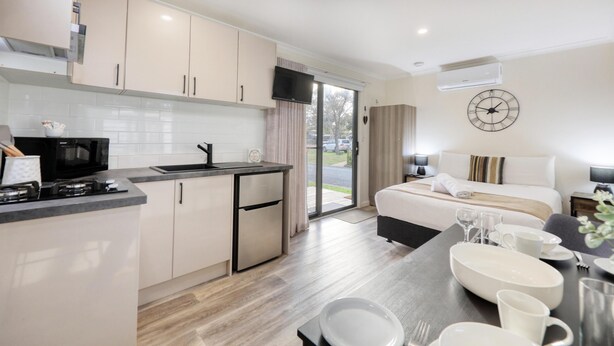 A modern hotel room with a kitchen, a dining area, and a bed. - Deniliquin Riverside Caravan Park (Deniliquin)