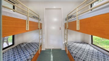 A room with two bunk beds, a door, and a window.