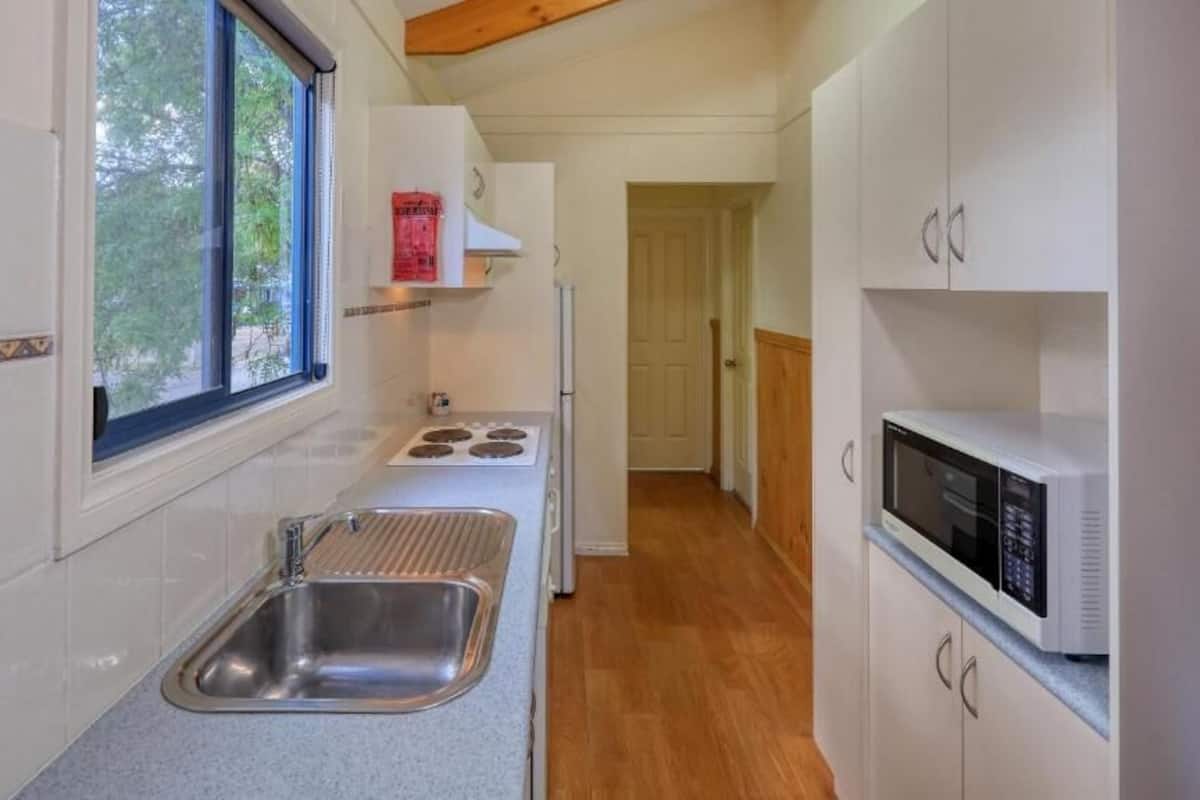 Una cocina compacta con lavamanos, estufa, microondas y armarios.