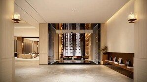 Un moderno vestíbulo de hotel con una fuente central, separaciones de vidrio y un mostrador de recepción.
