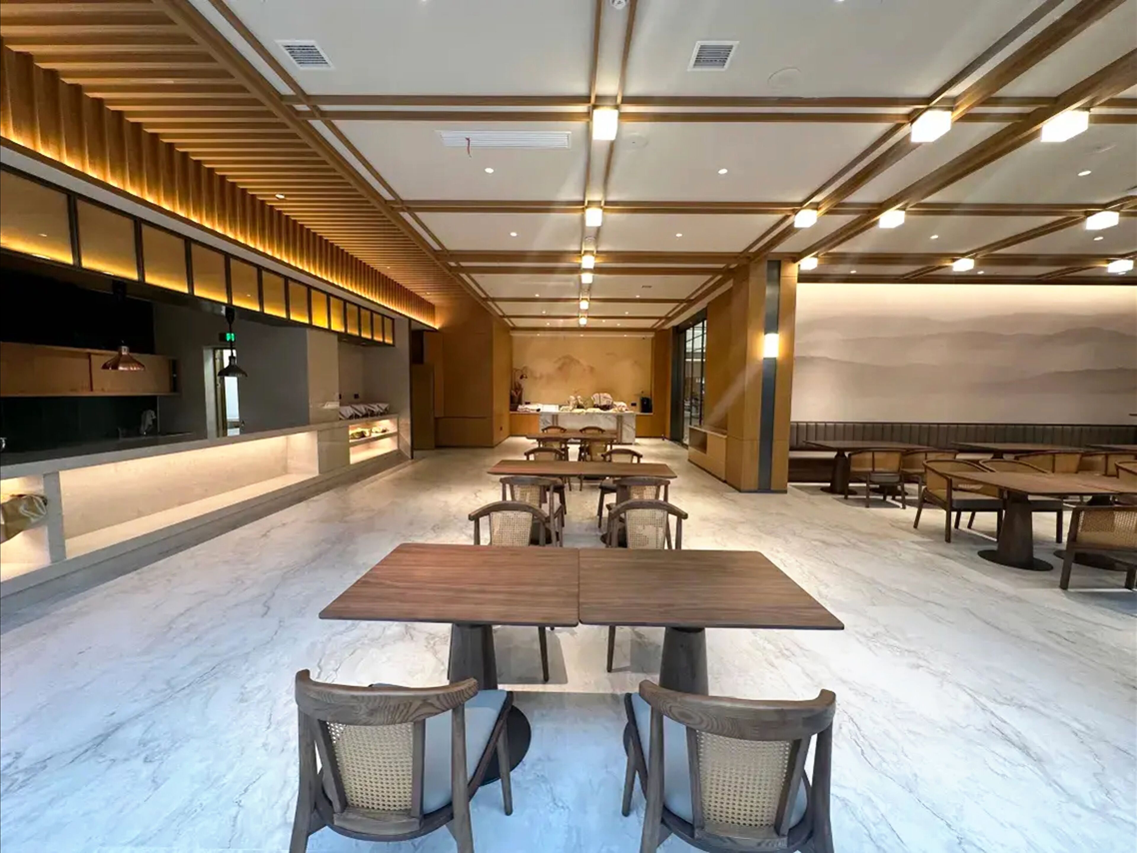 A spacious dining area with marble flooring, wooden tables, and chairs.