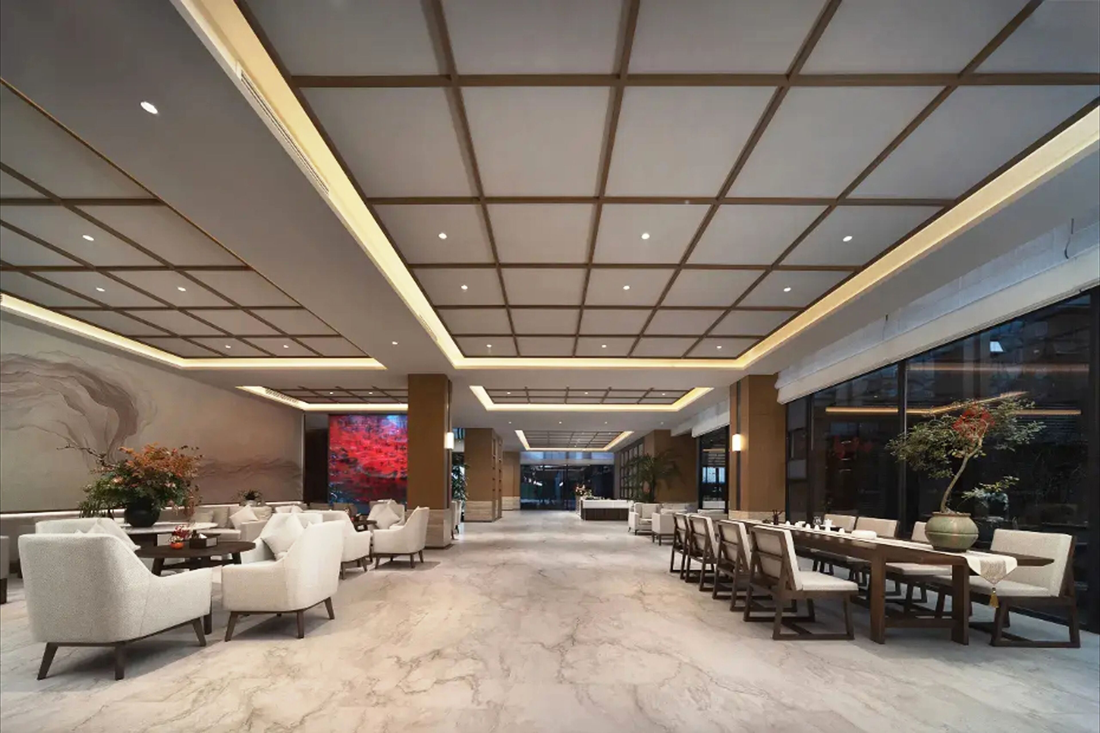 A spacious lobby with a marble floor, seating arrangements, and a large digital screen.