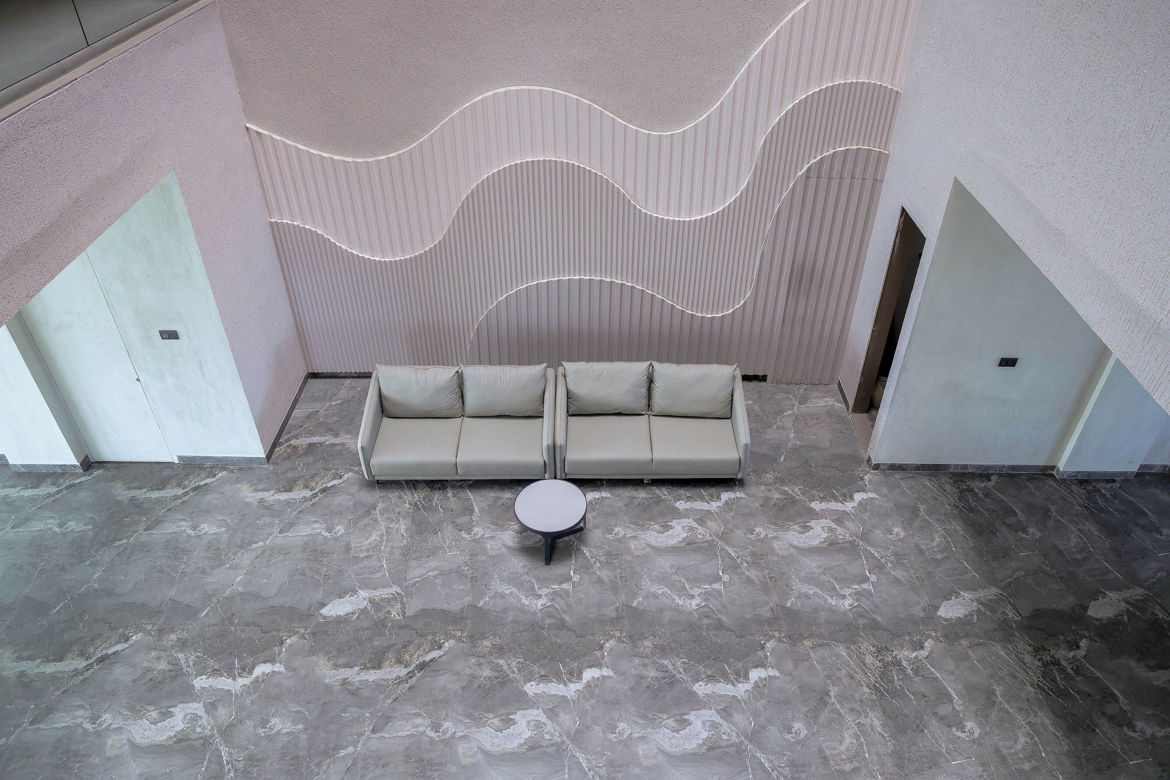 A modern interior with a sofa set, a round table, and a wavy ceiling design.