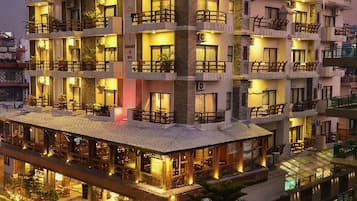 A multi-story hotel with balconies, a ground-level restaurant, and a sign indicating it is a luxury resort.