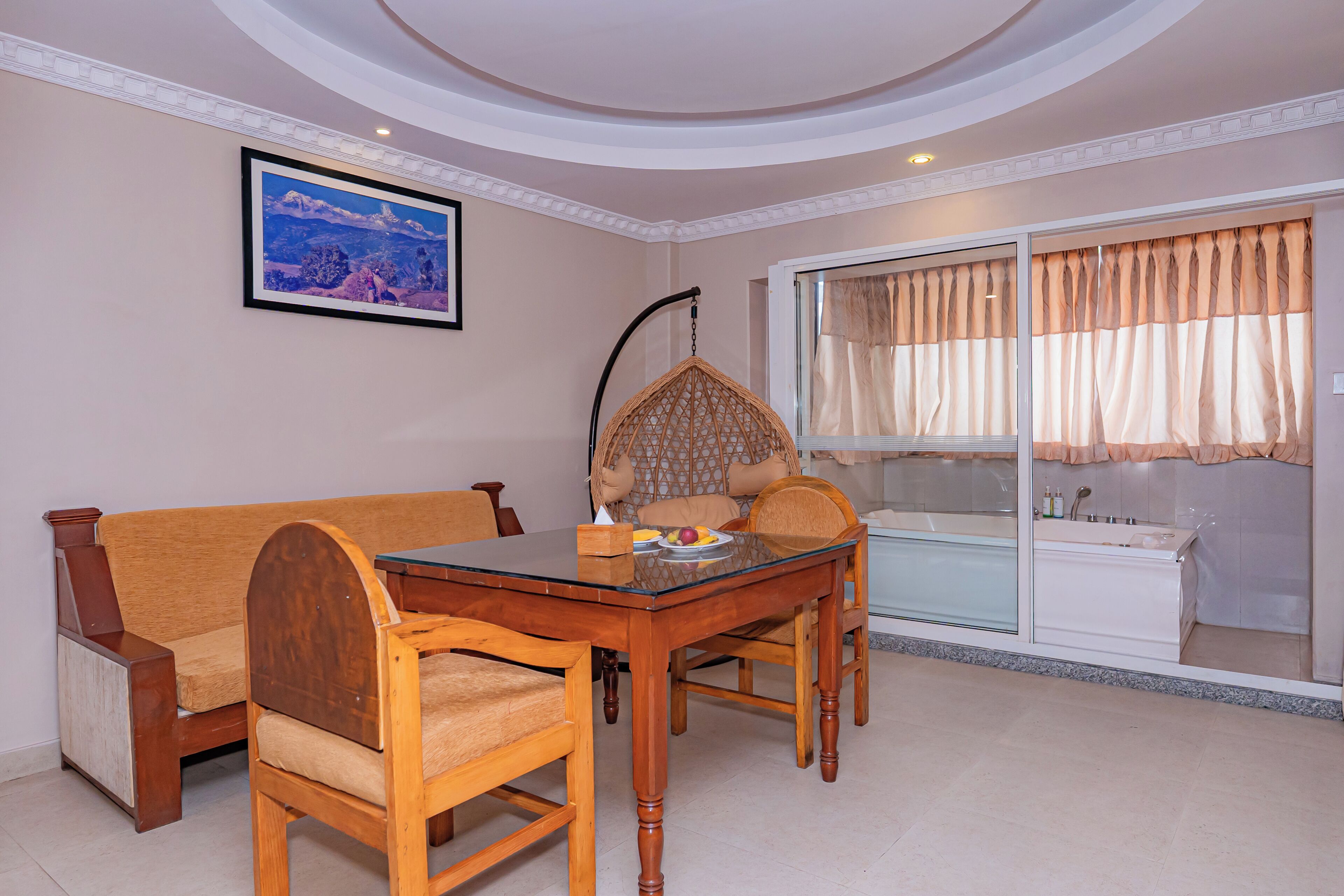A dining area with a glass-top table, wooden chairs, a cushioned sofa, a hanging chair, and a framed picture on the wall.