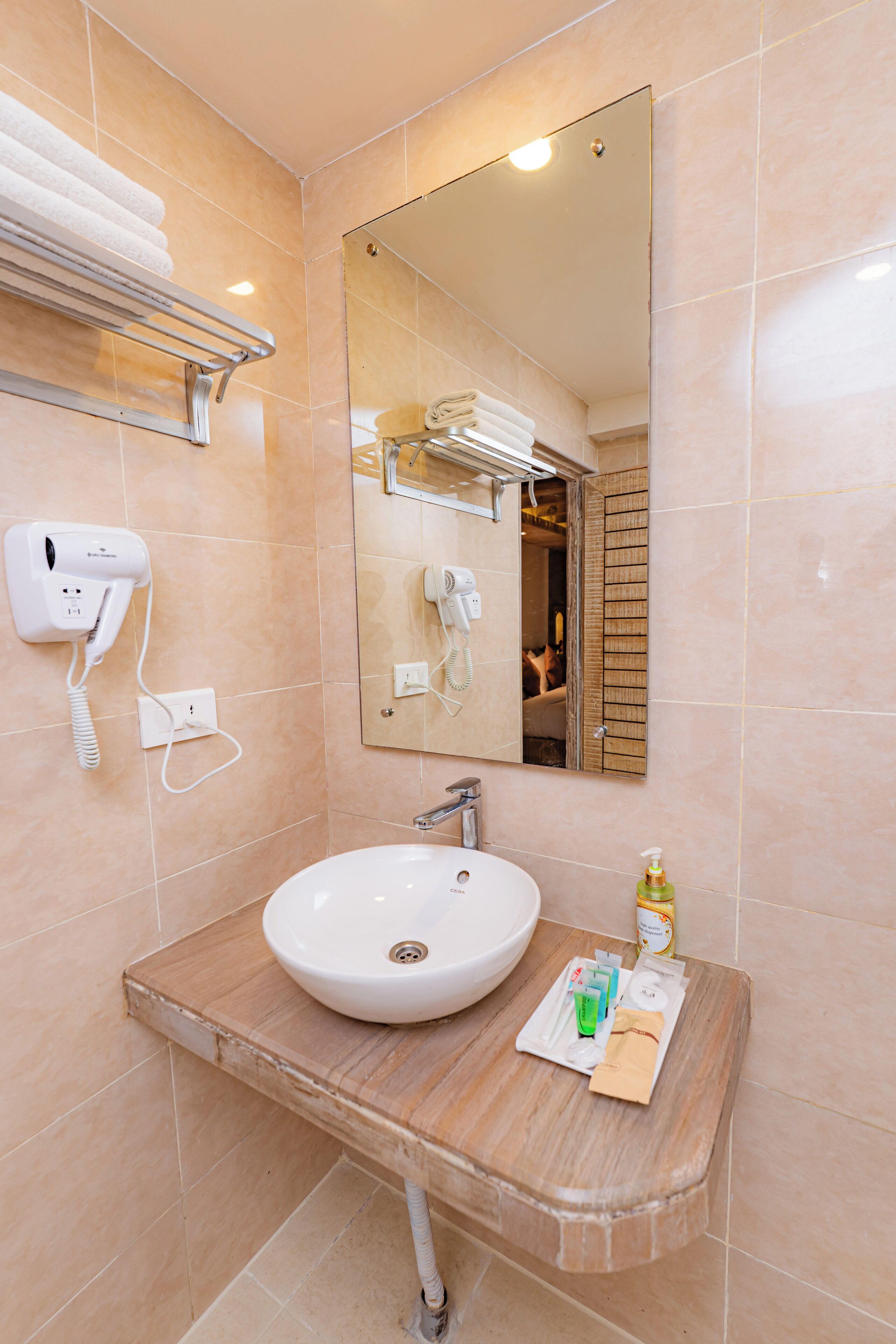 A bathroom with a sink, mirror, towel rack, hairdryer, and toiletries.