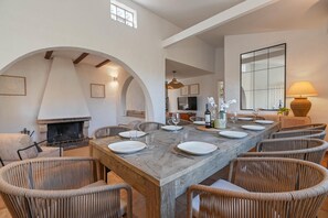A dining area with a long table, wicker chairs, a fireplace, and a large mirror. - Las Buganvillas - Javea, Costa Blanca (Javea)