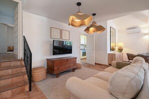 A living room with a sofa, television, wooden dresser, and a staircase. - Las Buganvillas - Javea, Costa Blanca (Javea)
