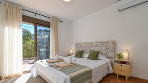 Ein Schlafzimmer mit einem Bett, Nachttischen, einem Wandbild und Blick durch eine Schiebetür.