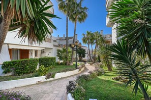 A courtyard with a pathway, palm trees, and white buildings with balconies. - Marysol - Javea, Costa Blanca (Javea)