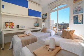 A hotel room with two beds, a desk, a window with a balcony view, and artwork on the walls. - Marysol - Javea, Costa Blanca (Javea)
