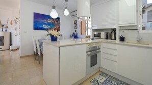 Eine moderne Küche mit weißen Schränken, einer zentralen Kochinsel und einem Essbereich mit Stühlen.