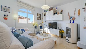 Ein modernes Wohnzimmer mit einer Couch, Couchtisch, Fernseher und Kamin.