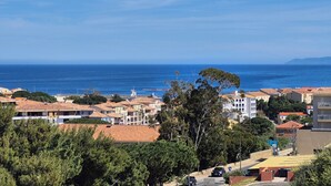 Un pueblo costero con edificios, cielo despejado y el mar al fondo.