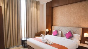 A hotel room with a large bed, a chair, a nightstand, and a lamp. - Sanzha Chulha Hotel (Varanasi)