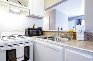 A kitchen with a stove, microwave, sink, and cabinets. - Studio @ Montrose 04! Downtown, Medical Center, Stadium (Houston)
