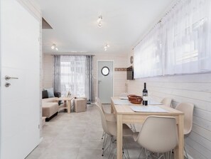 A modern, well-lit room with a dining area, a sofa set, and a kitchen counter. - Cottage in Pobierowo Near Baltic Beach (Rewal)