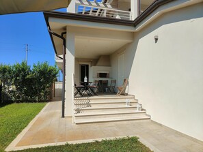 A residential building with a balcony, outdoor seating, and a staircase leading to the entrance. - Holiday Home Casa Simone in Lido (Camaiore)