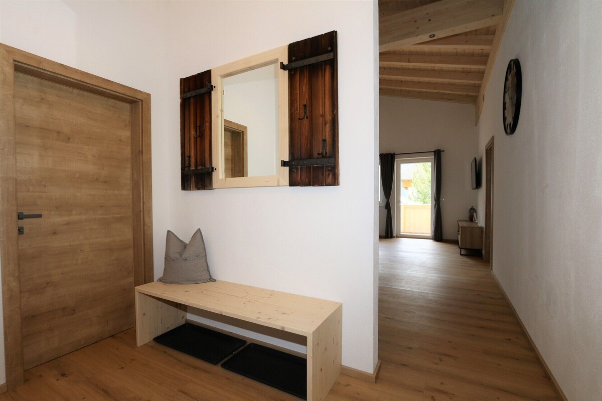 Ein Flur mit einer Holzbank, einer Tür und einem Spiegel mit Holzläden.