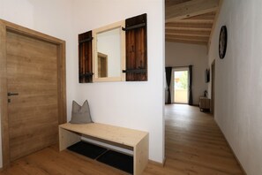 A hallway with a wooden bench, a door, and a mirror with wooden shutters. - Apartment in Milders With Stubai Supercard (Neustift Im Stubaital)