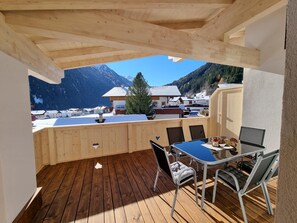 A wooden deck with a table and chairs, overlooking a mountain landscape. - Apartment in Milders With Stubai Supercard (Neustift Im Stubaital)