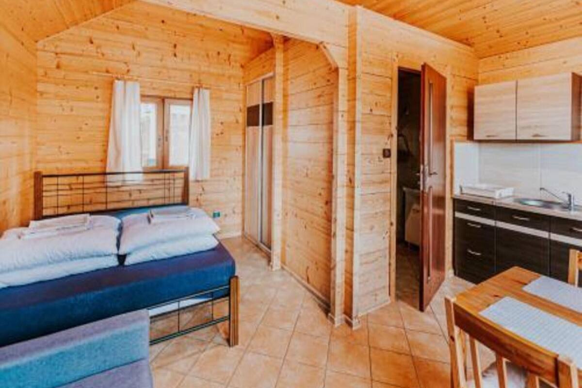 Eine Holzhütte mit einem Bett, einem kleinen Tisch und einer Küchenzeile.