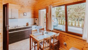 A wooden cabin interior with a kitchen, dining area, and large windows. - Single-story Holiday Homes Close to the Beach (Ustronie Morskie)
