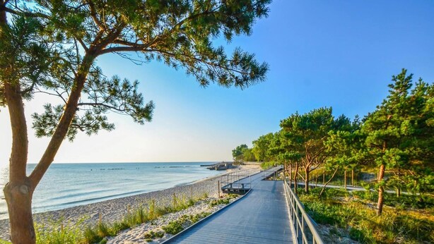 A coastal walkway with a metal railing, leading to a beach. - Single-story Holiday Homes Close to the Beach (Ustronie Morskie)