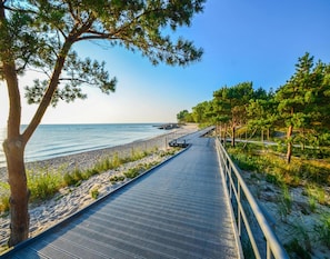 A coastal walkway with a metal railing, leading to a beach. - Single-story Holiday Homes Close to the Beach (Ustronie Morskie)