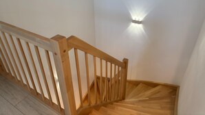 En trätrappa med ett ledstång och en väggmonterad lampa.