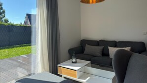 Ett modernt vardagsrum med en soffa, ett sidobord och en hängande lampa.