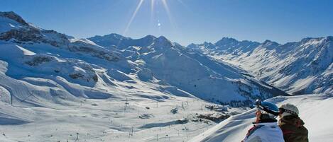 A snowy mountain landscape with a clear sky and a bright sun.