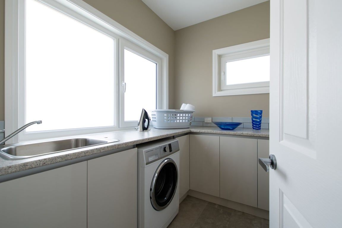 A compact kitchen with a built-in washer, a sink, and a window providing natural light.