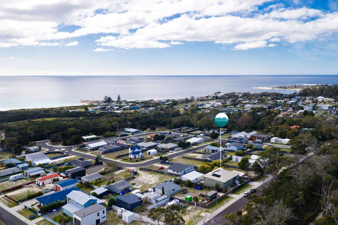 A residential area with houses, a road, and a body of water in the background.