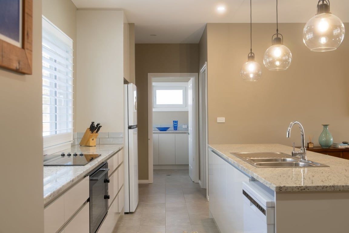 A modern kitchen with a central island, a built-in oven, and a sink.