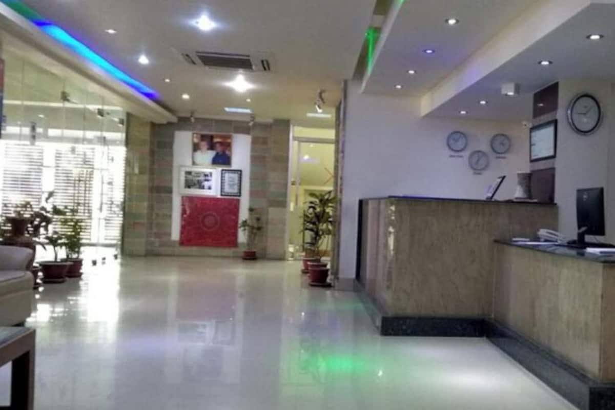 A hotel lobby with a reception desk, a clock, and a red accent wall.