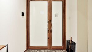 Uma porta de madeira com puxador e uma pequena placa na parede.