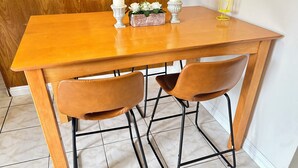 A wooden dining table with two brown chairs, a white candle, and a small flower arrangement.