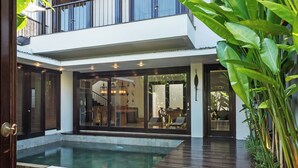 Ein modernes Haus mit Pool, großen Fenstern und einem Balkon.