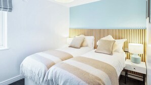 Ett hotellrum med en säng, sängbord, en lampa och ett fönster.