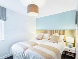 Et hotelværelse med seng, sengeborde, lampe og et vindue.