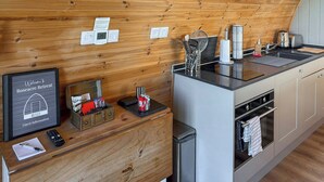 A kitchen with wooden walls, a skylight, a sink, a stove, and a trash bin. - The Welbury - UKC9285 (Brompton)