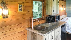L’intérieur d’un chalet en bois comprend un coin cuisine équipé d’un évier, d’une machine à café et d’un placard.