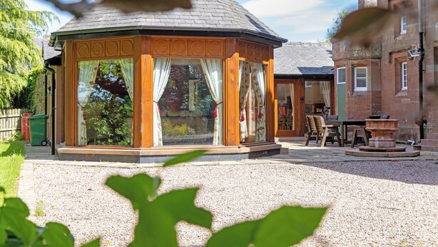 A gazebo with a tiled roof, large windows, and a gravel ground. - Heads Nook Hall Cottage (Brampton)