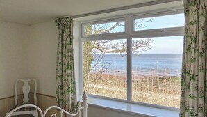 Ein Zimmer mit einem Bett, einem fensterartigen Ausblick und Blick auf den Strand.