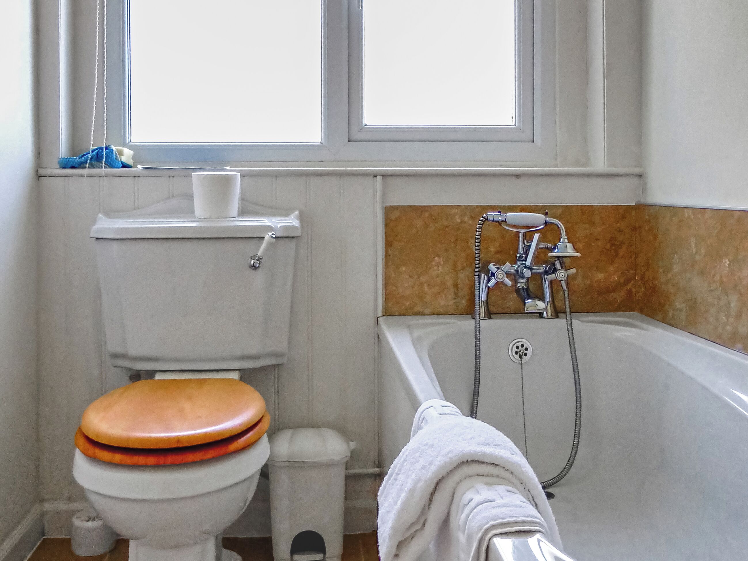 A bathroom with a toilet, a bathtub, and a window.