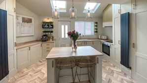 A modern kitchen with a central island, pendant lighting, and a herringbone floor pattern. - 2 bedroom accommodation in Newcastle Upon Tyne (Newcastle Upon Tyne)