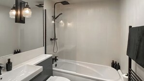 A modern bathroom with a bathtub, toilet, and vanity with a mirror. - 2 bedroom accommodation in Newcastle Upon Tyne (Newcastle Upon Tyne)